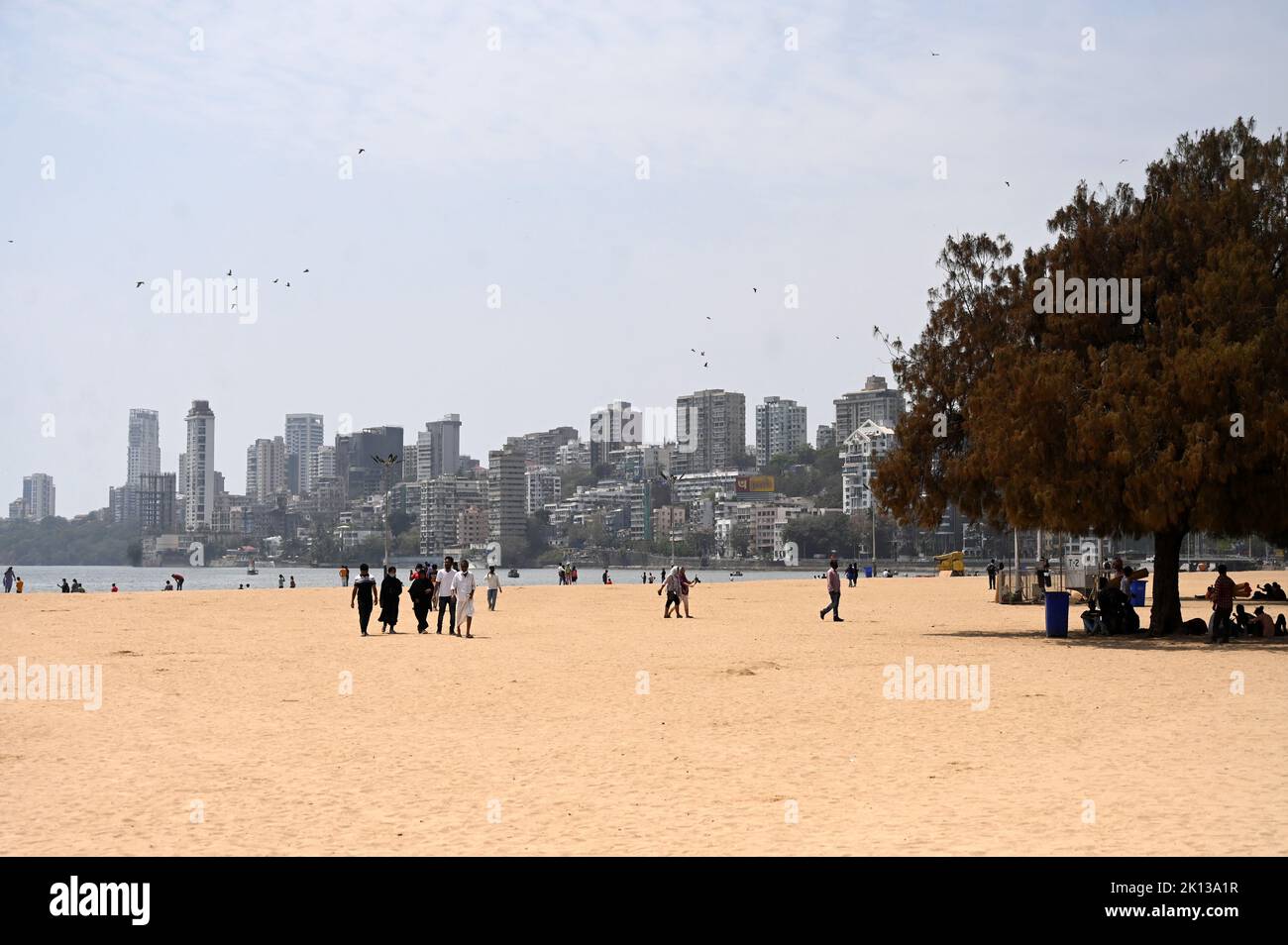 Les gens se balader sur la plage de Juhu, les immeubles de la ville en hauteur en arrière-plan, Mumbai, Inde, Asie Banque D'Images