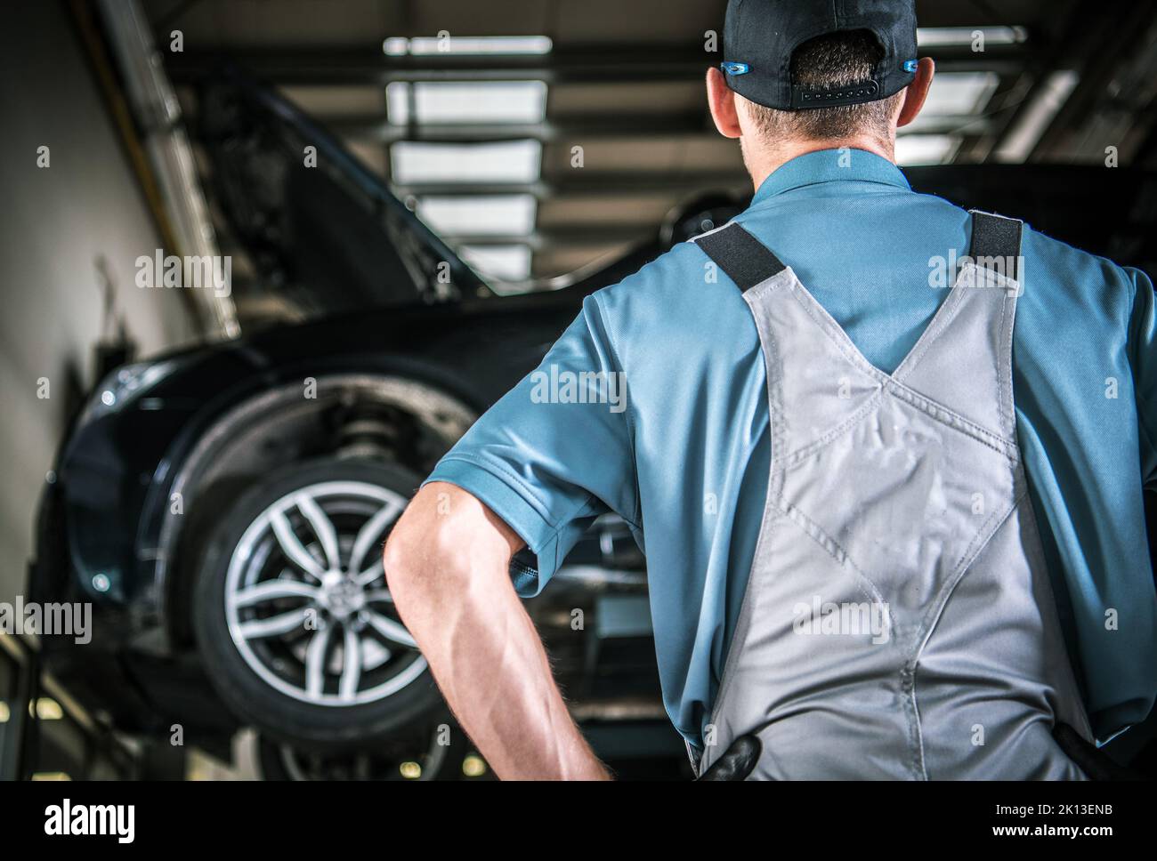 Mécanicien d'entretien de voiture caucasien devant le véhicule soulevé. Thème de l'industrie automobile. Banque D'Images