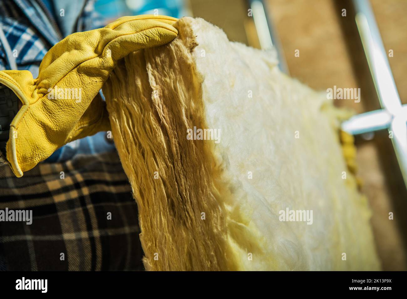 Gros plan d'un travailleur de la construction tenant un morceau de matériau isolant en laine minérale dans ses mains. Isolation thermique à économie d'énergie. Banque D'Images