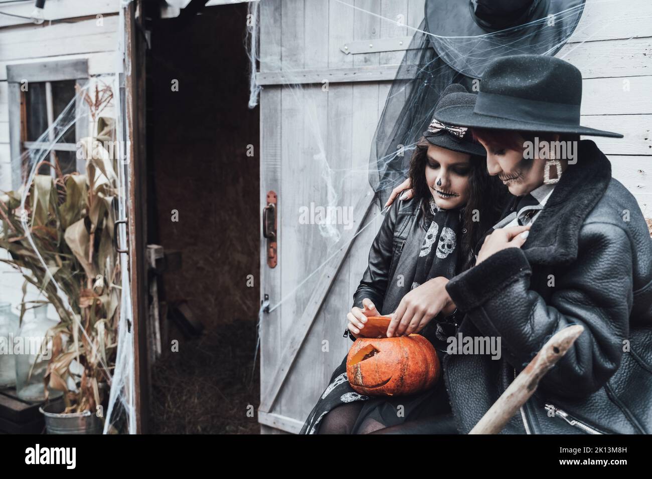 Famille, mère et fille effrayantes célébrant halloween. Grange de rue. Citrouille jack-o-lanterne.terrifiant crâne noir maquillage demi-visage et sorcières costumes, br Banque D'Images