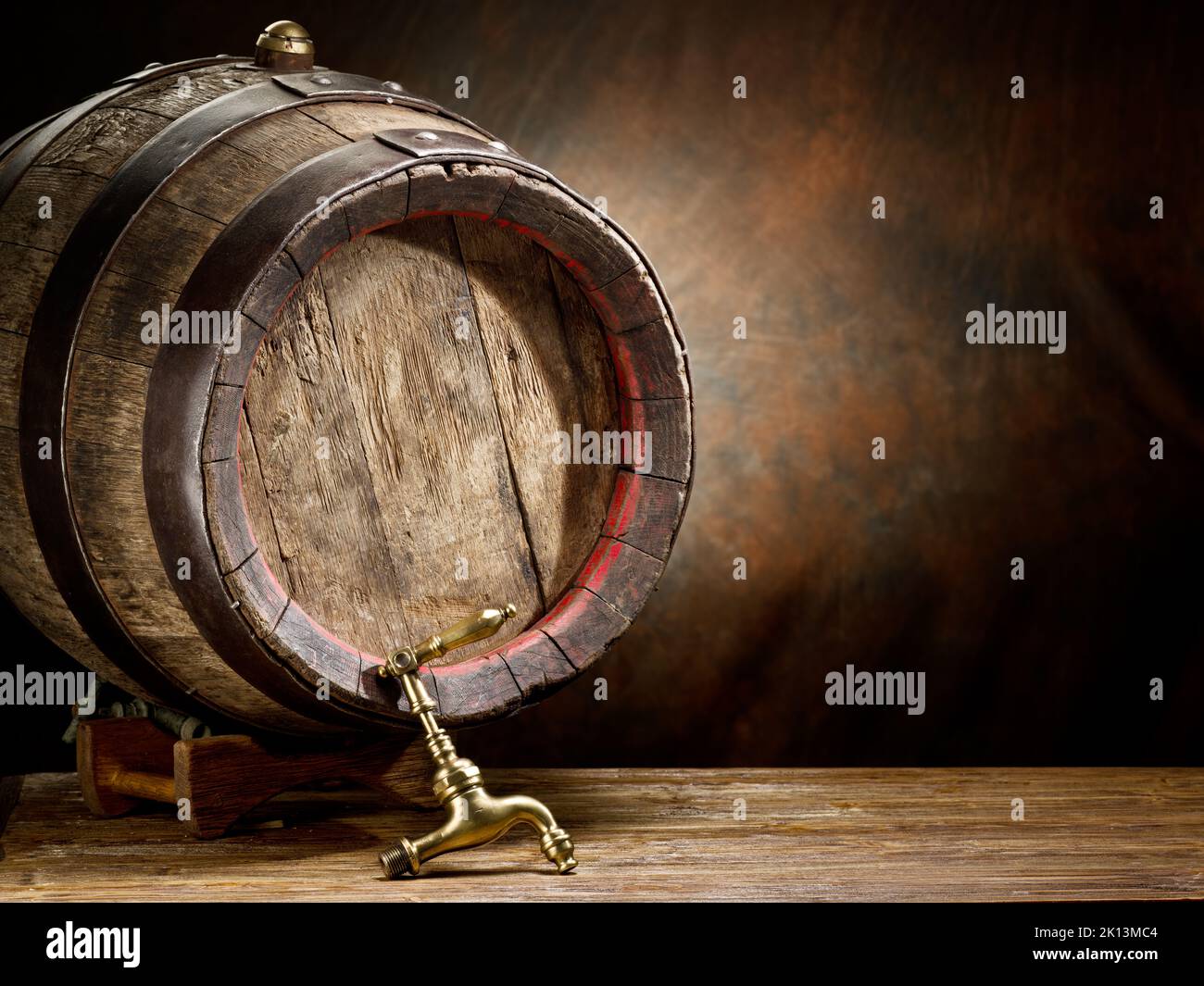 Fût de vin ou de bière en bois avec des cerceaux métalliques sur la table en bois sur fond marron. Banque D'Images