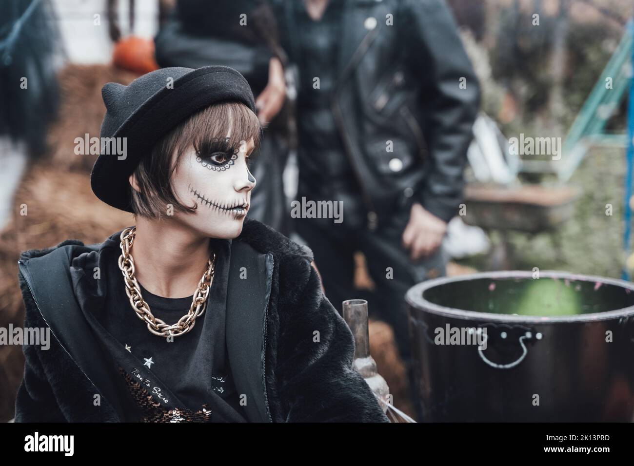 Belle petite fille effrayante célébrant halloween. Terrifiant noir, blanc demi-visage maquillage et costume de sorcière, image élégante. Horreur, plaisir chez les enfants Banque D'Images