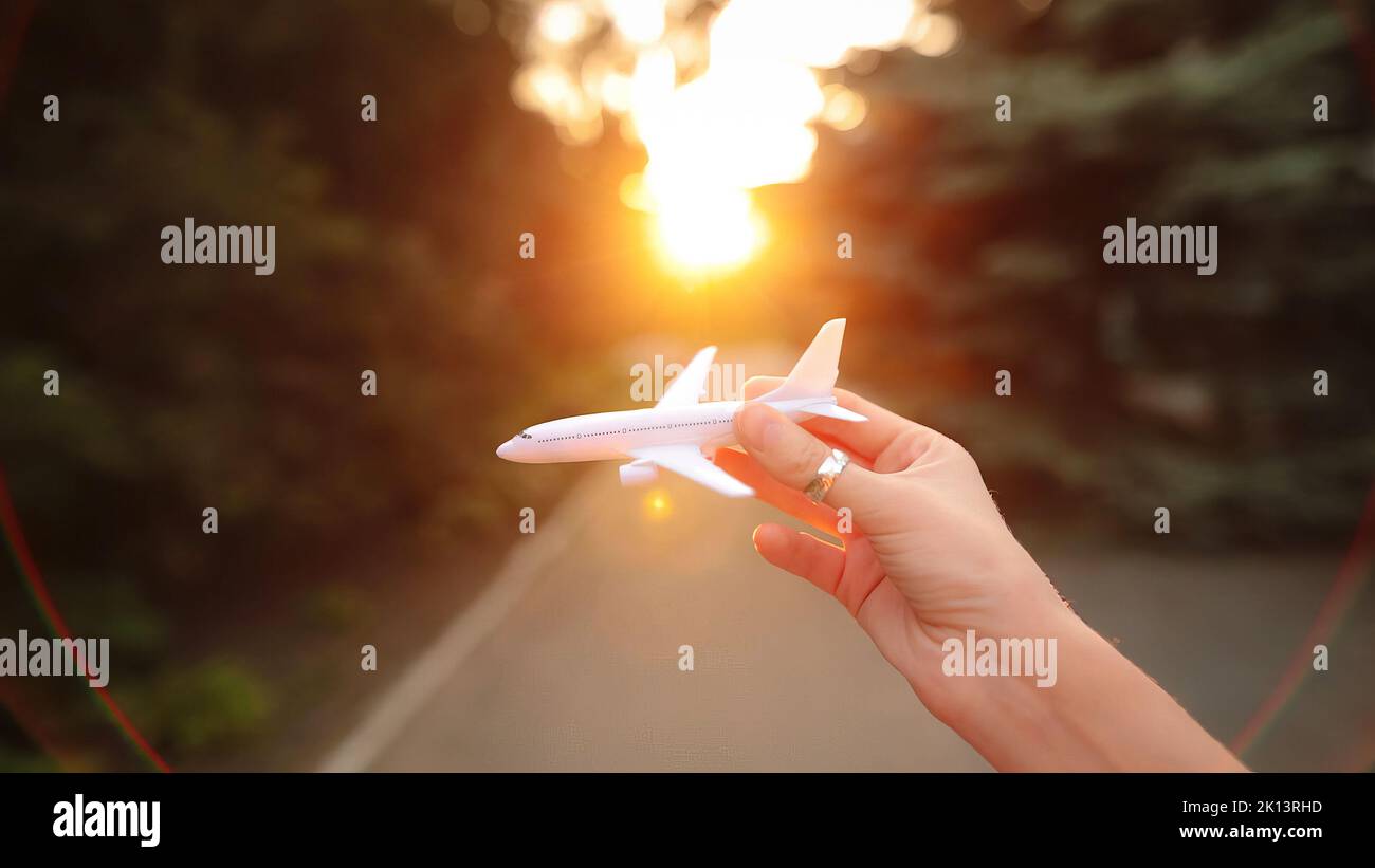 La main femelle simule un vol avec un avion en plastique dans la soirée. Banque D'Images