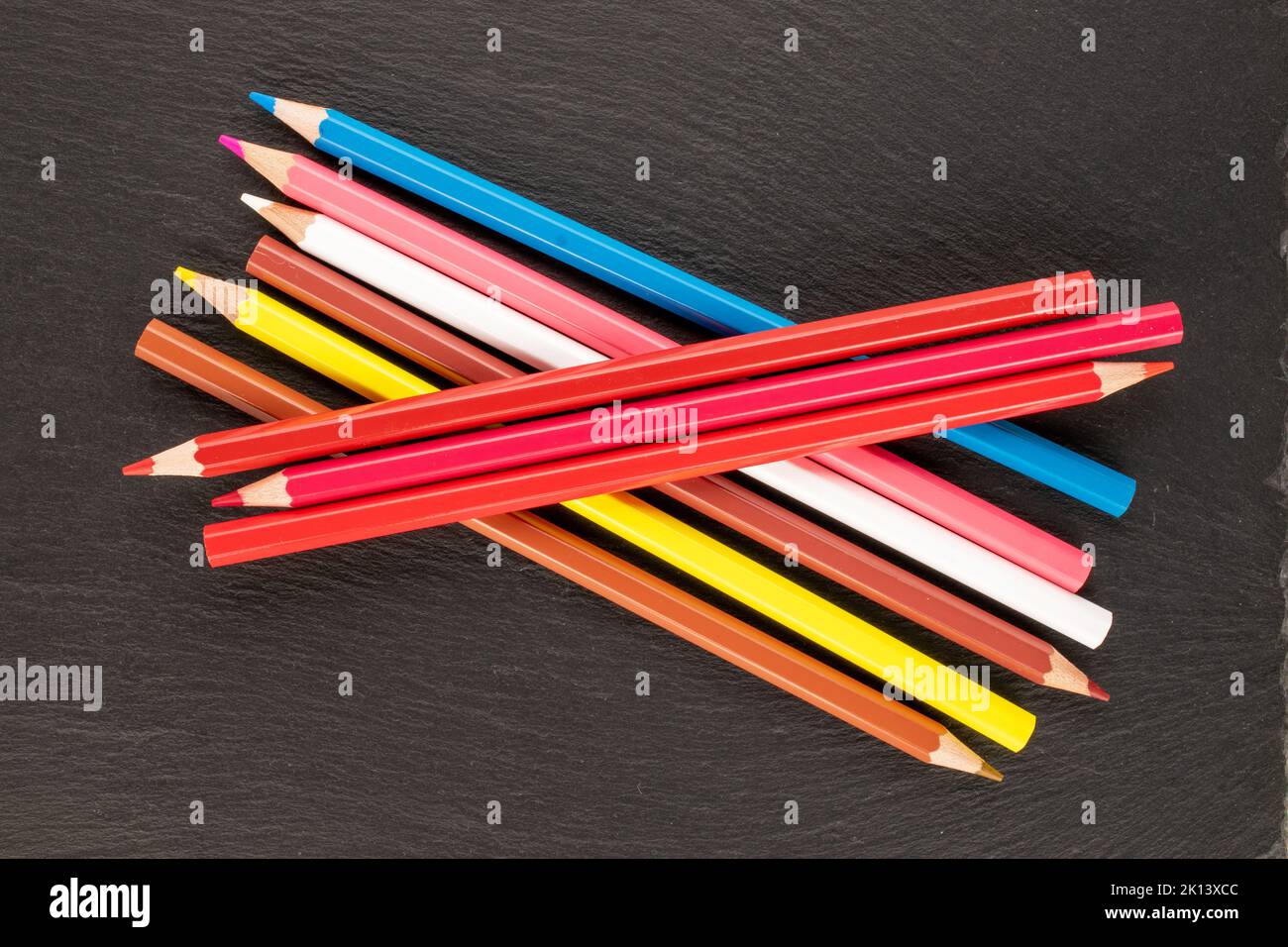 Plusieurs crayons de couleur sur des pierres d'ardoise, gros plan, vue de dessus. Banque D'Images