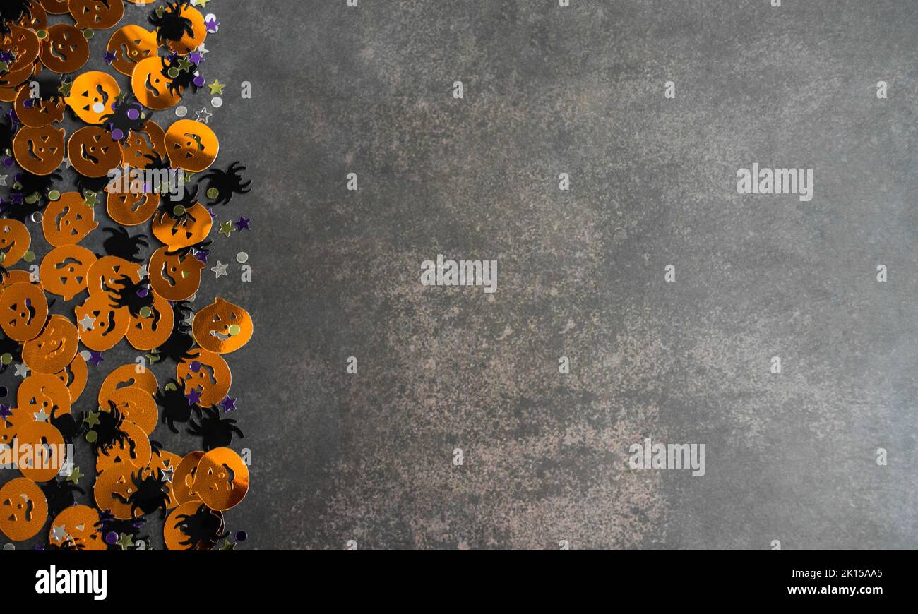 Halloween fond: Confetti en forme de citrouilles orange, araignées noires et étoiles. Arrière-plan gris. Copier l'espace. Banque D'Images