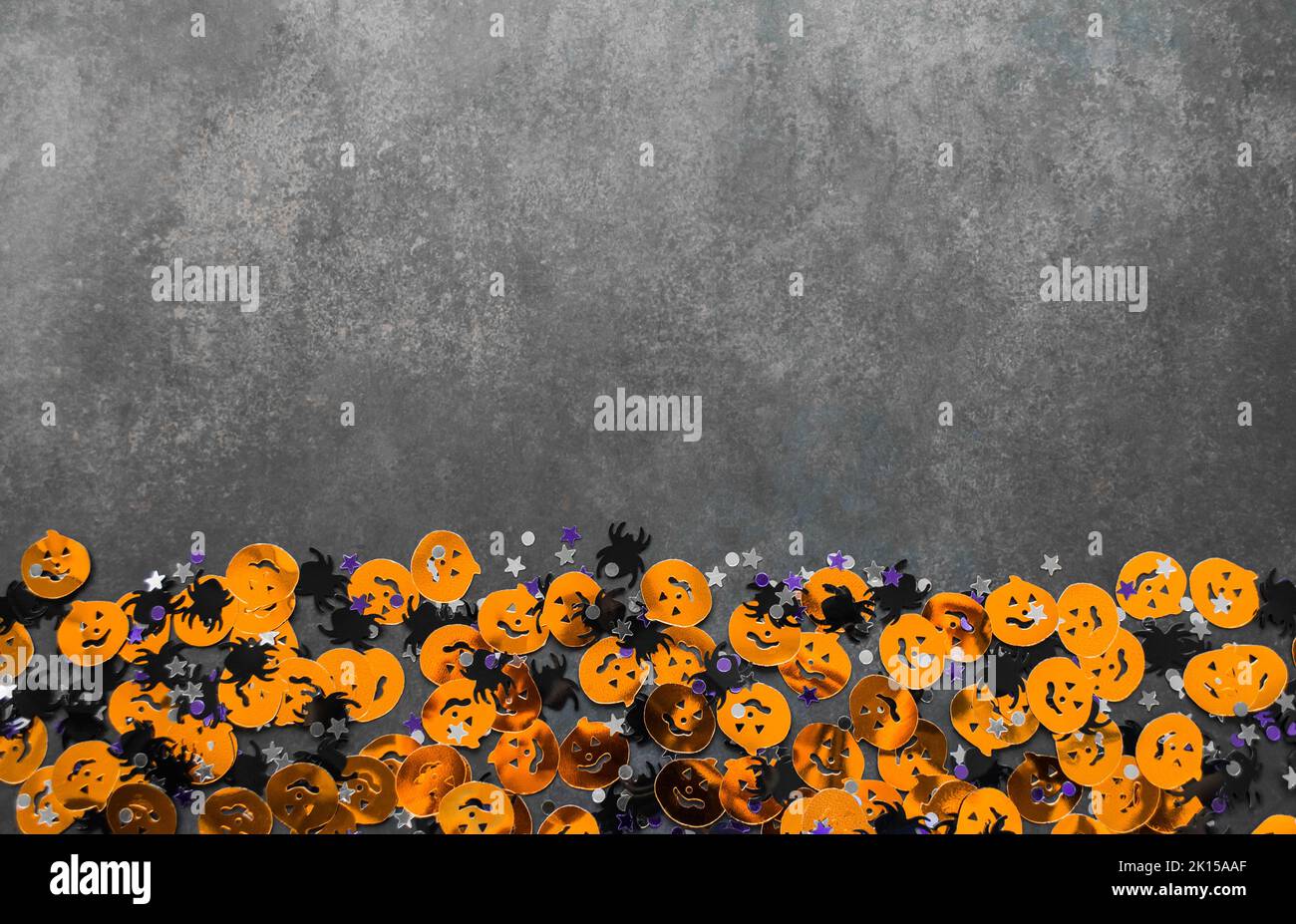 Halloween fond: Confetti en forme de citrouilles orange, araignées noires et étoiles. Arrière-plan gris. Copier l'espace. Banque D'Images