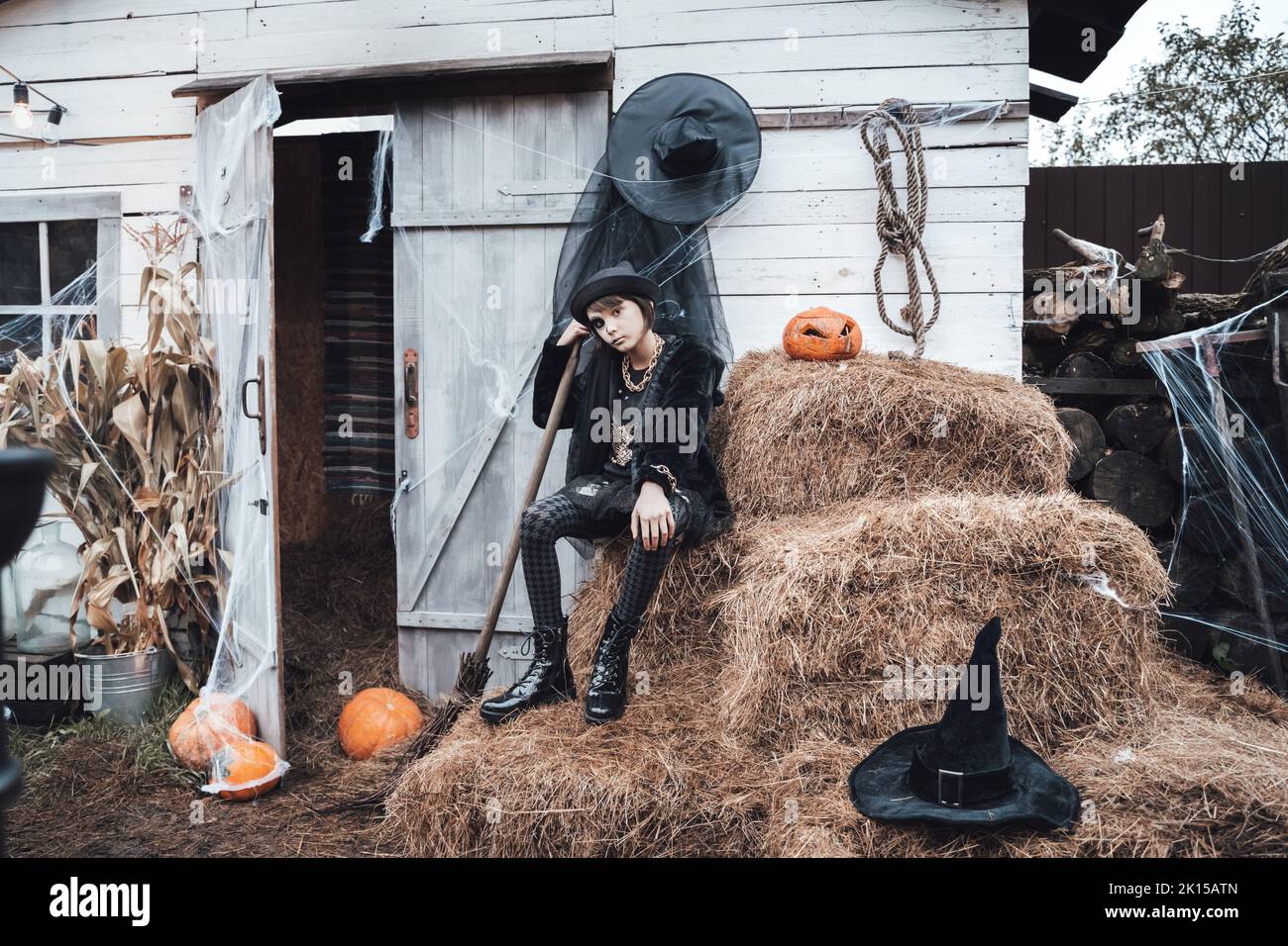 Belle petite fille effrayante célébrant halloween. Un maquillage noir et blanc terrifiant pour les demi-visages, un costume de sorcière, une image élégante. Amusez-vous à la fête des enfants en b Banque D'Images