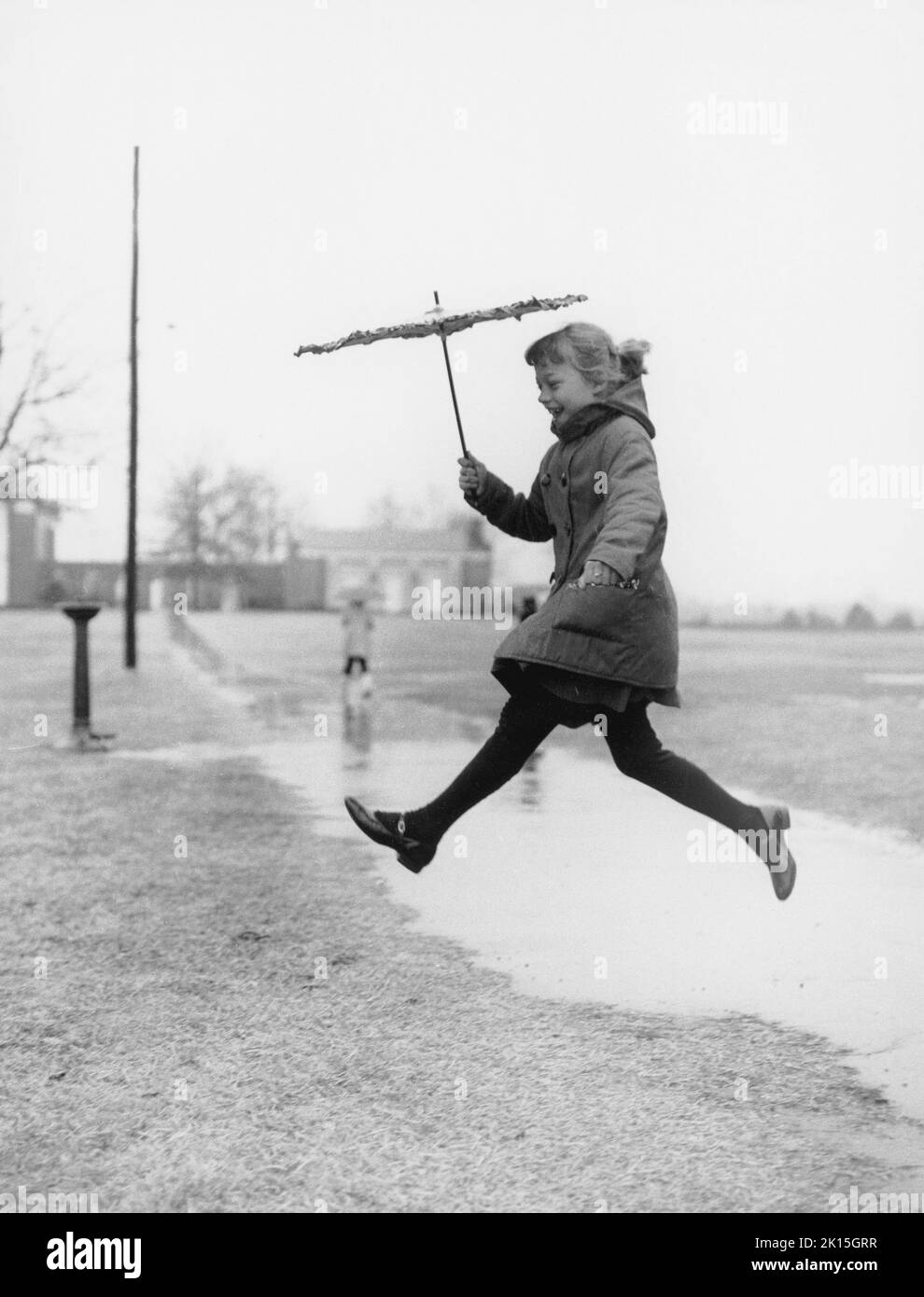 Une jeune fille saute sur une flaque.1960s. Banque D'Images