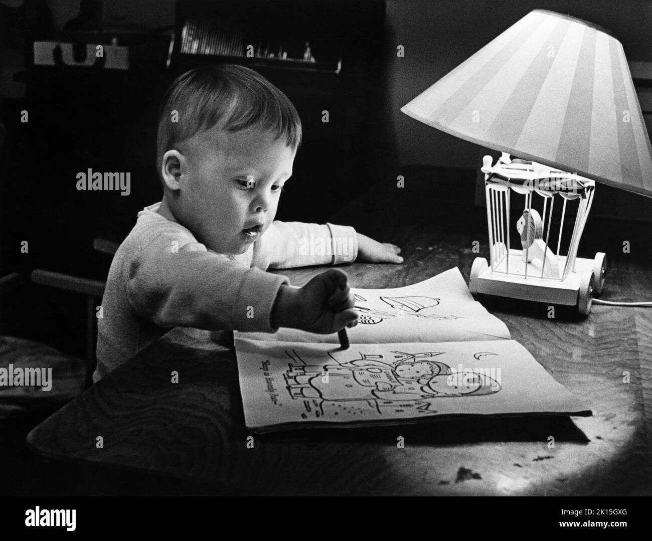 Un enfant de syndrome de downes coloriant un livre. Banque D'Images