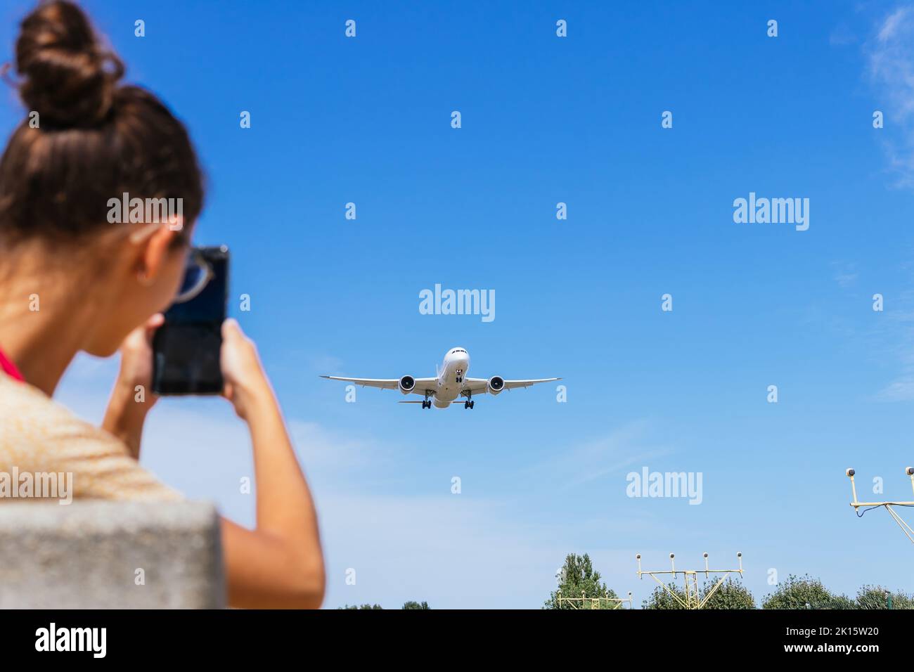 Vue arrière d'une femelle non reconnaissable dans des vêtements décontractés prenant des photos avec un smartphone pour voler contre le ciel bleu Banque D'Images