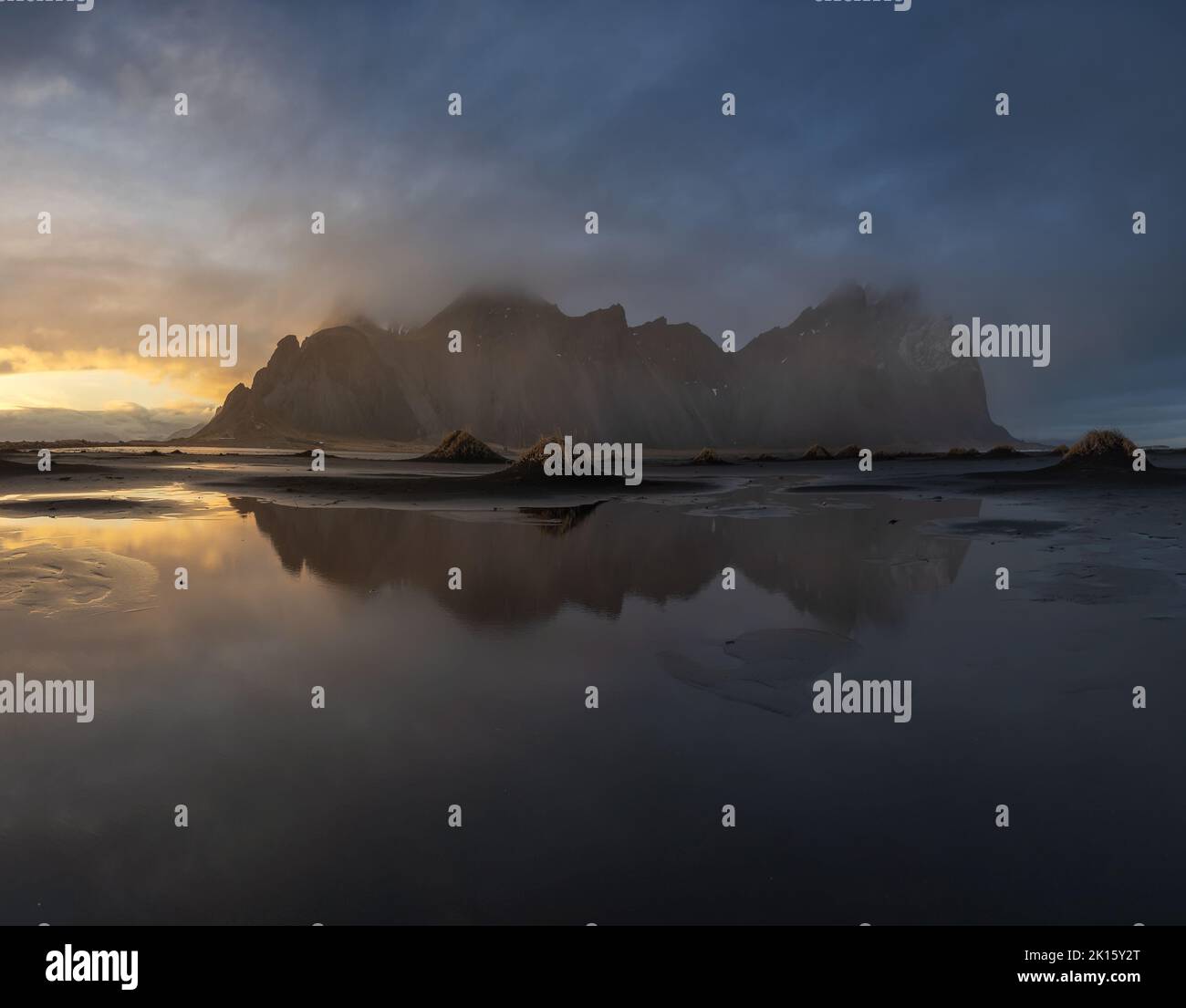 Vue spectaculaire sur l'eau calme et la montagne Vestrahorn située contre le ciel nuageux de lever du soleil en hiver matin en Islande Banque D'Images