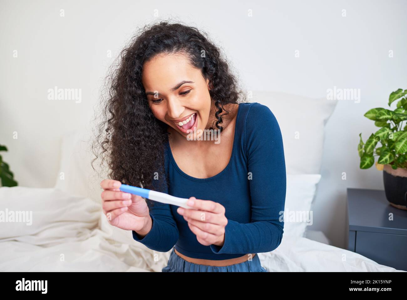 Une jeune femme multiethnique est extatique et heureuse de voir les résultats des tests de grossesse Banque D'Images
