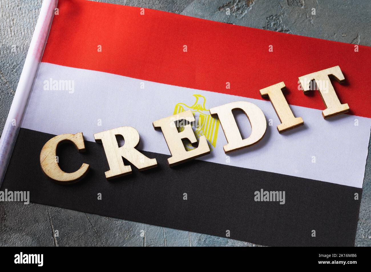 Texte de lettres en bois et drapeau égyptien sur fond abstrait, concept d'utilisation de crédit en Egypte Banque D'Images