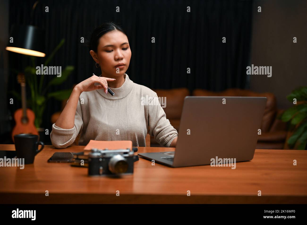 Femme d'affaires ou chef d'entreprise asiatique du millénaire, concentrée et professionnelle, travaillant de nuit à domicile sur son projet d'informatique sur ordinateur portable. Banque D'Images