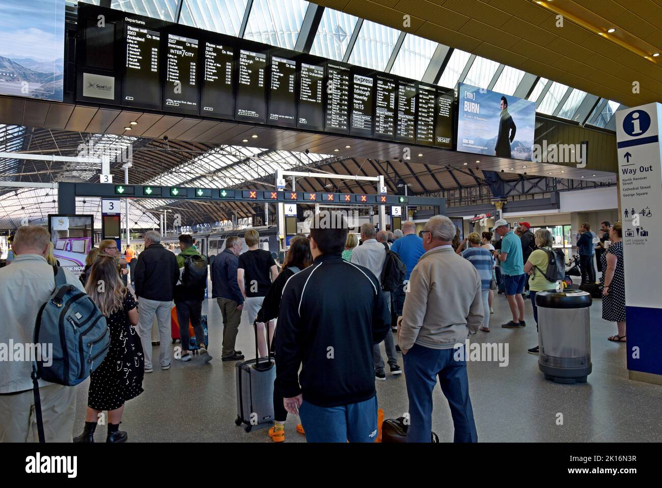 Passagers attendant des trains qui regardent les panneaux de départ à la gare Queen Street Station, Glasgow, Écosse, Royaume-Uni Banque D'Images
