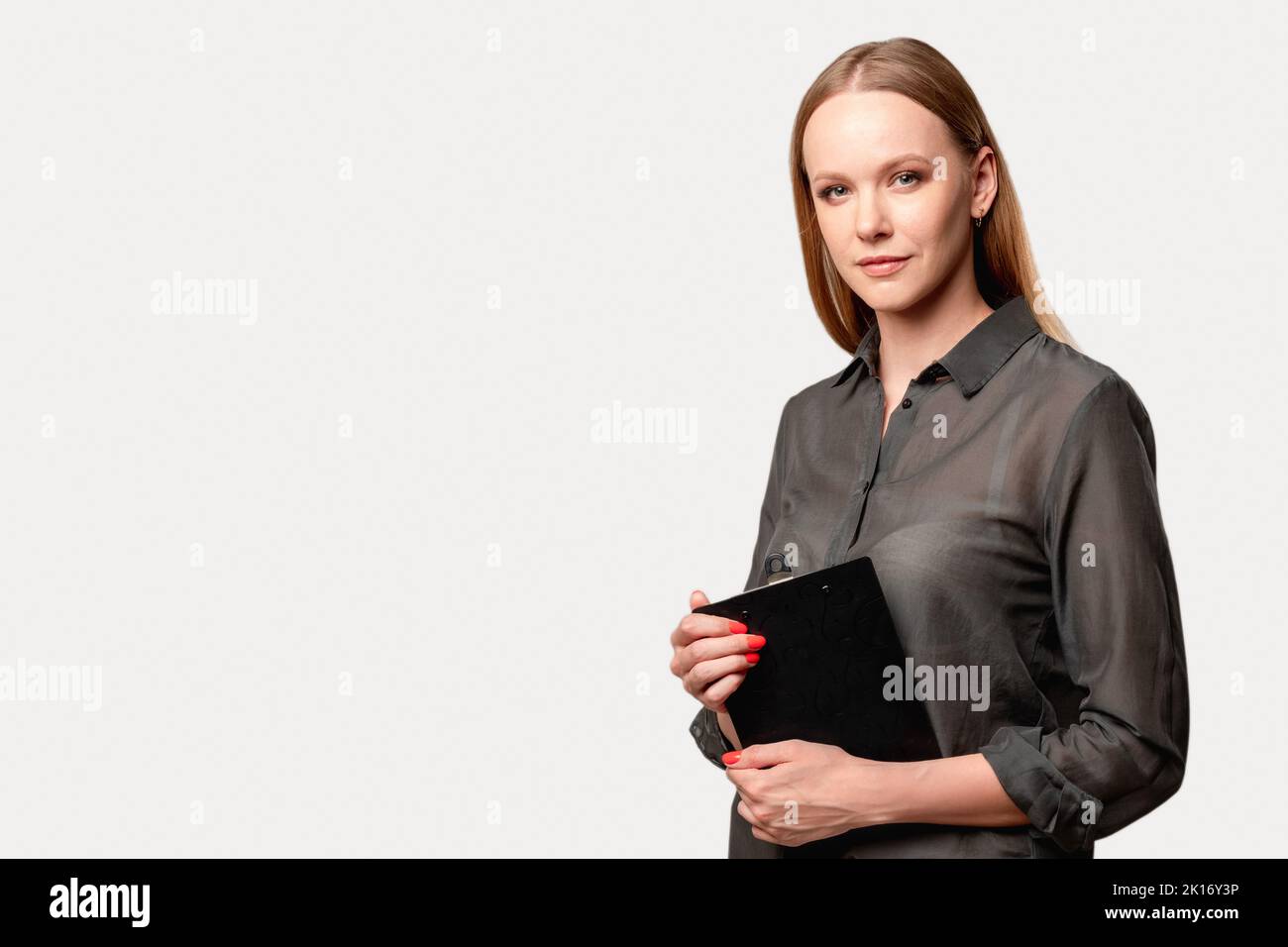 Femme confiante. Coaching d'entreprise. Leadership féminin. Carrière réussie. Portrait de la dame ambitieuse en chemise grise avec presse-papiers regardant l'appareil photo est Banque D'Images