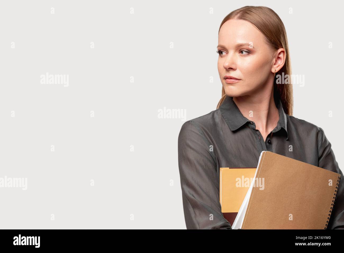 Femme confiante. Coaching d'entreprise. Croissance de l'auto-développement. Démarrage réussi. Portrait d'une femme ambitieuse en chemise grise avec des livres isolés à la lumière Banque D'Images