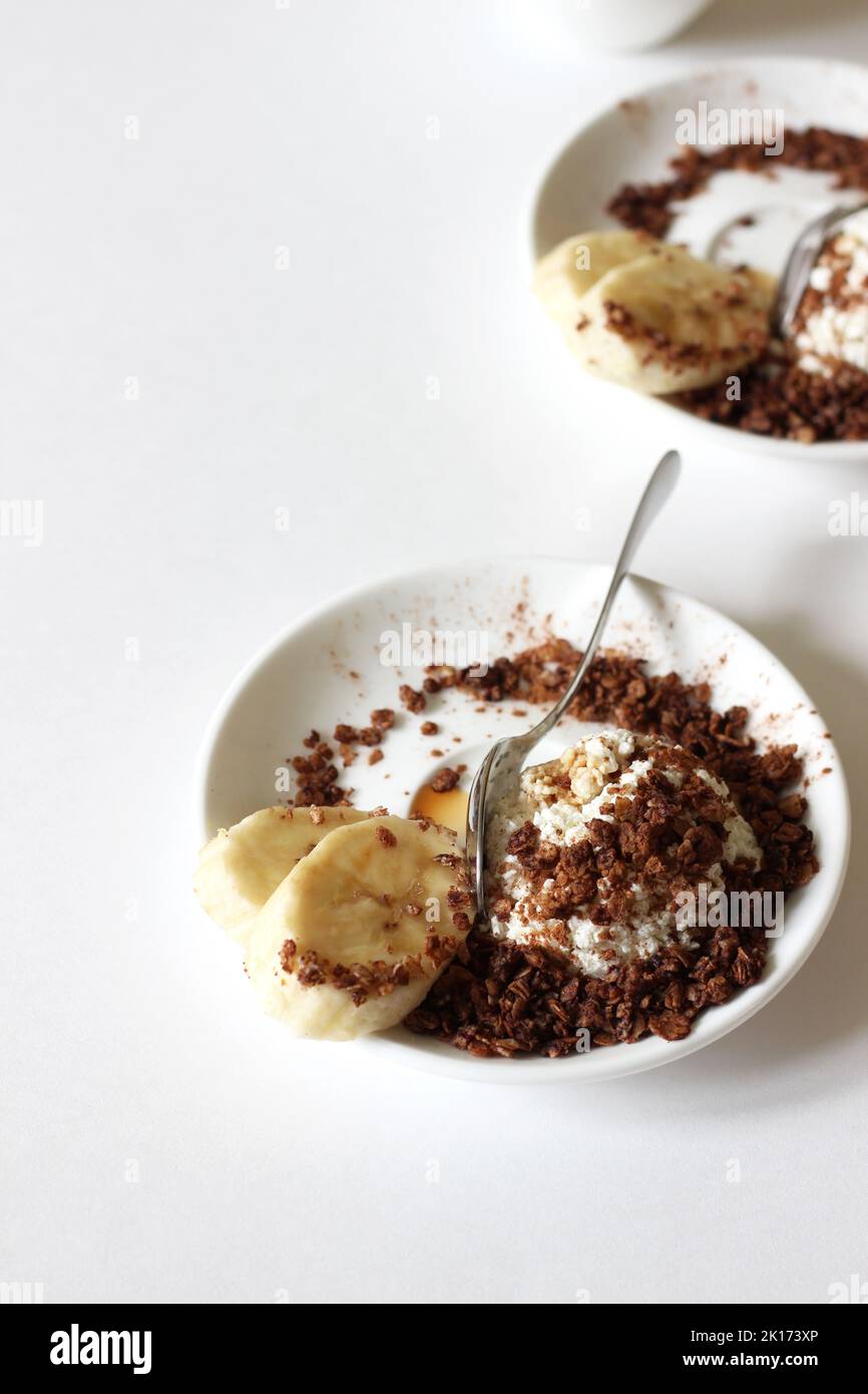 Fromage cottage avec granola maison, cannelle, miel, banane. Un petit déjeuner sain et sucré. Banque D'Images