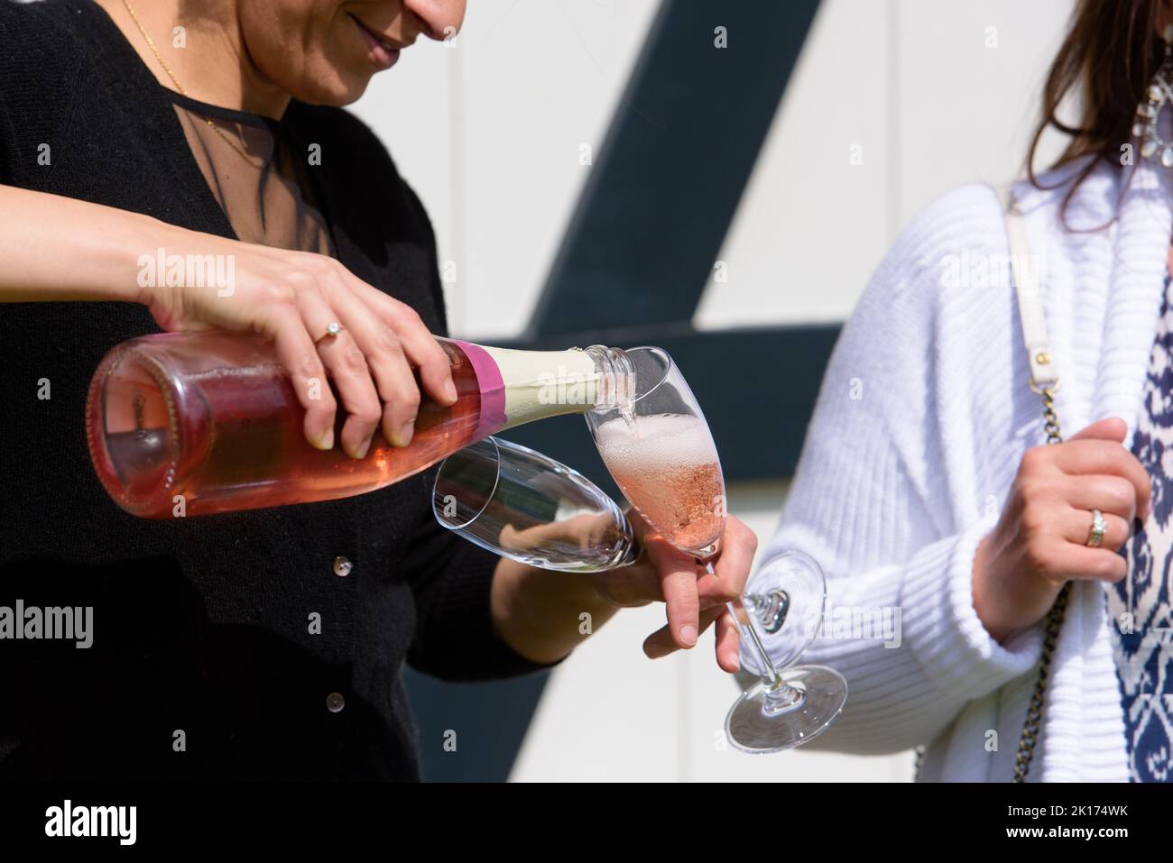 gros plan d'une bouteille de champagne pooring du champagne rose dans une flûte à champagne contre une personne floue lors d'une fête Banque D'Images