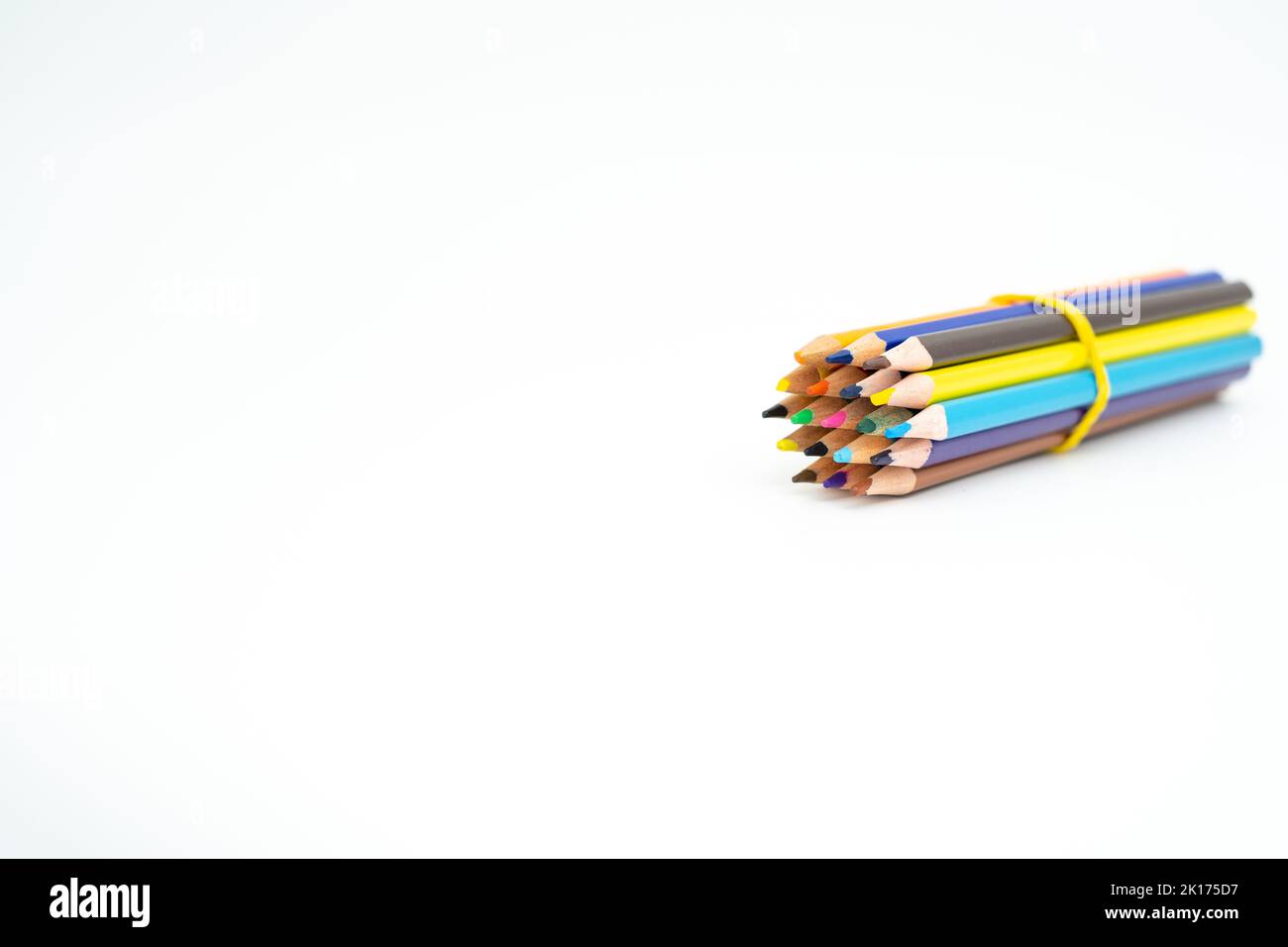 Crayons de couleur bois rassemblés dans un paquet avec une bande de caoutchouc sur un fond blanc avec un point (plomb) en évidence Banque D'Images