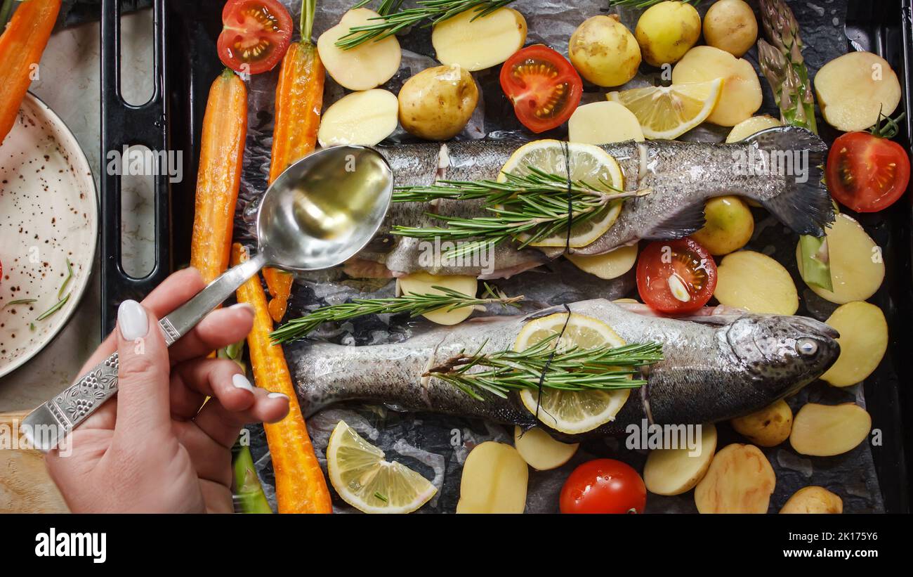 Préparation du poisson-bar pour la cuisson sur le gril avec des herbes aromatiques et des légumes sur une planche de bois vue du dessus Banque D'Images