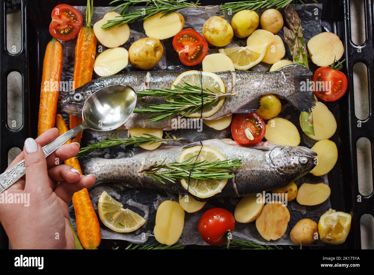 Préparation du poisson-bar pour la cuisson sur le gril avec des herbes aromatiques et des légumes sur une planche de bois vue du dessus Banque D'Images