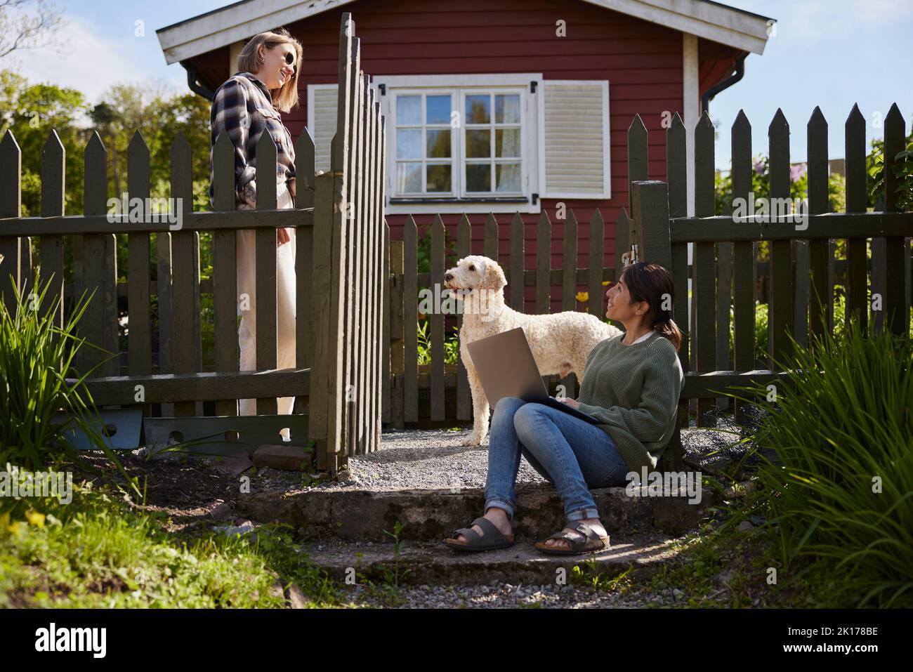 Femmes avec ordinateur portable en face de la maison en bois Banque D'Images