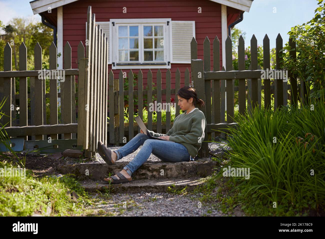 Femme avec ordinateur portable en face de la maison en bois Banque D'Images