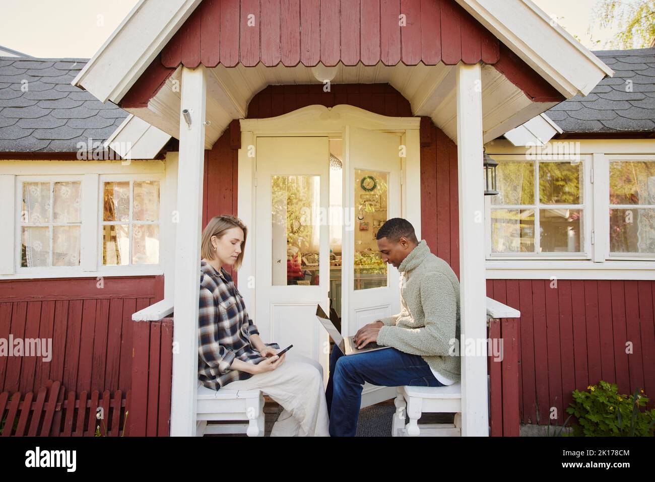 Couple assis en face de la maison en bois Banque D'Images