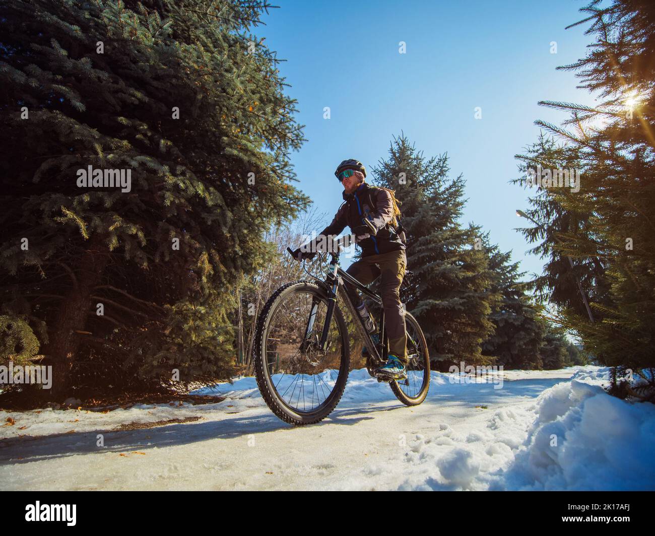 Un homme barbu fait du vélo en hiver dans le parc. Passe-temps actif en hiver. Vélo comme transport écologique Banque D'Images