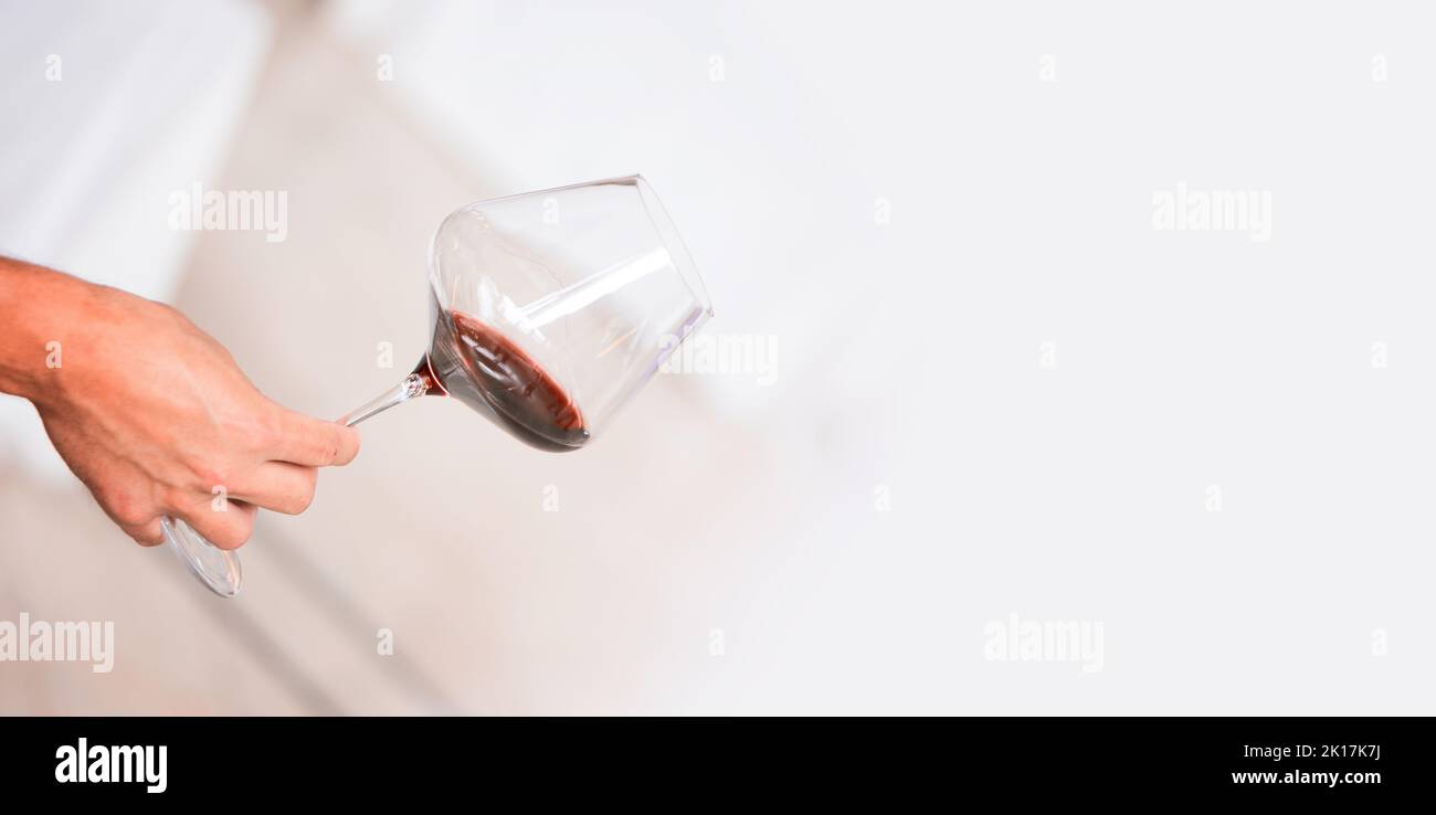 Verre de vin rouge à la main sur la dégustation de boissons alcoolisées image pour bannières, poster, magazine, Flayer, maquette. Banque D'Images