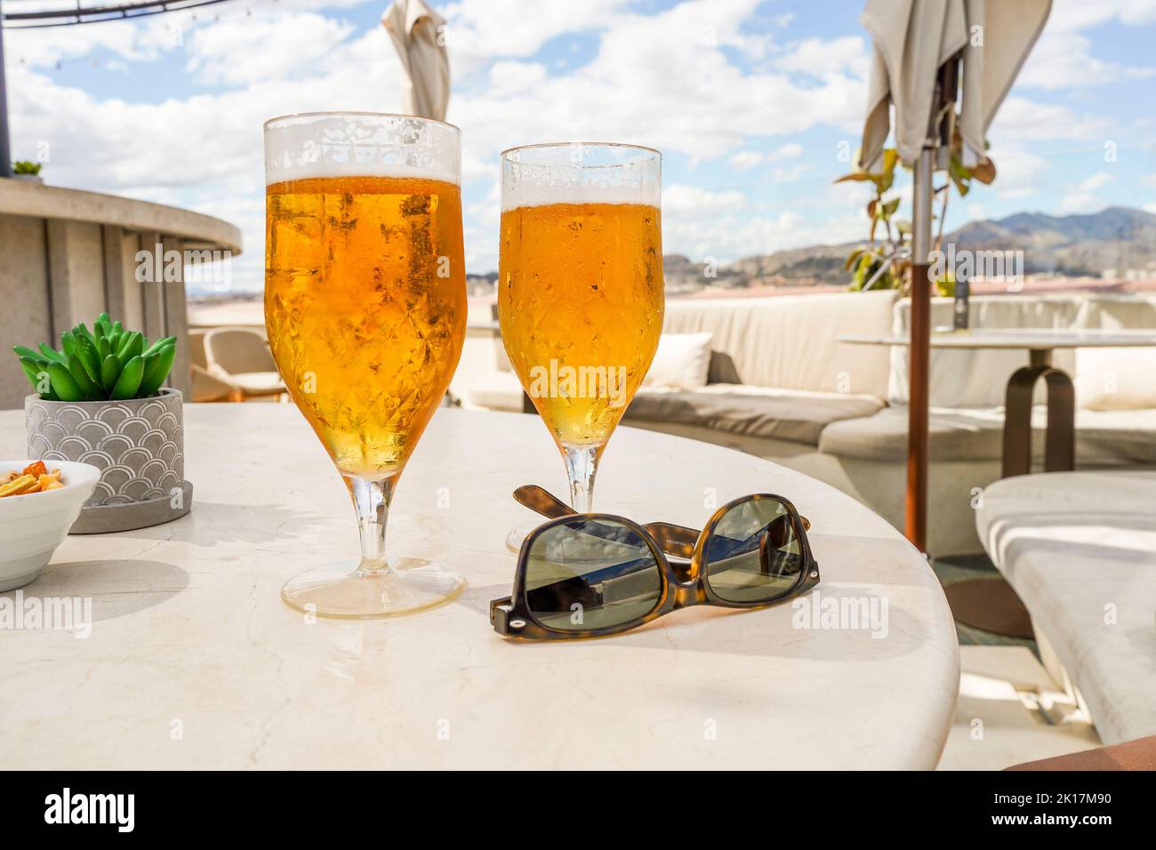 Deux verres avec bière et lunettes de soleil sur une table sur un toit-terrasse, restaurant, Espagne. Banque D'Images