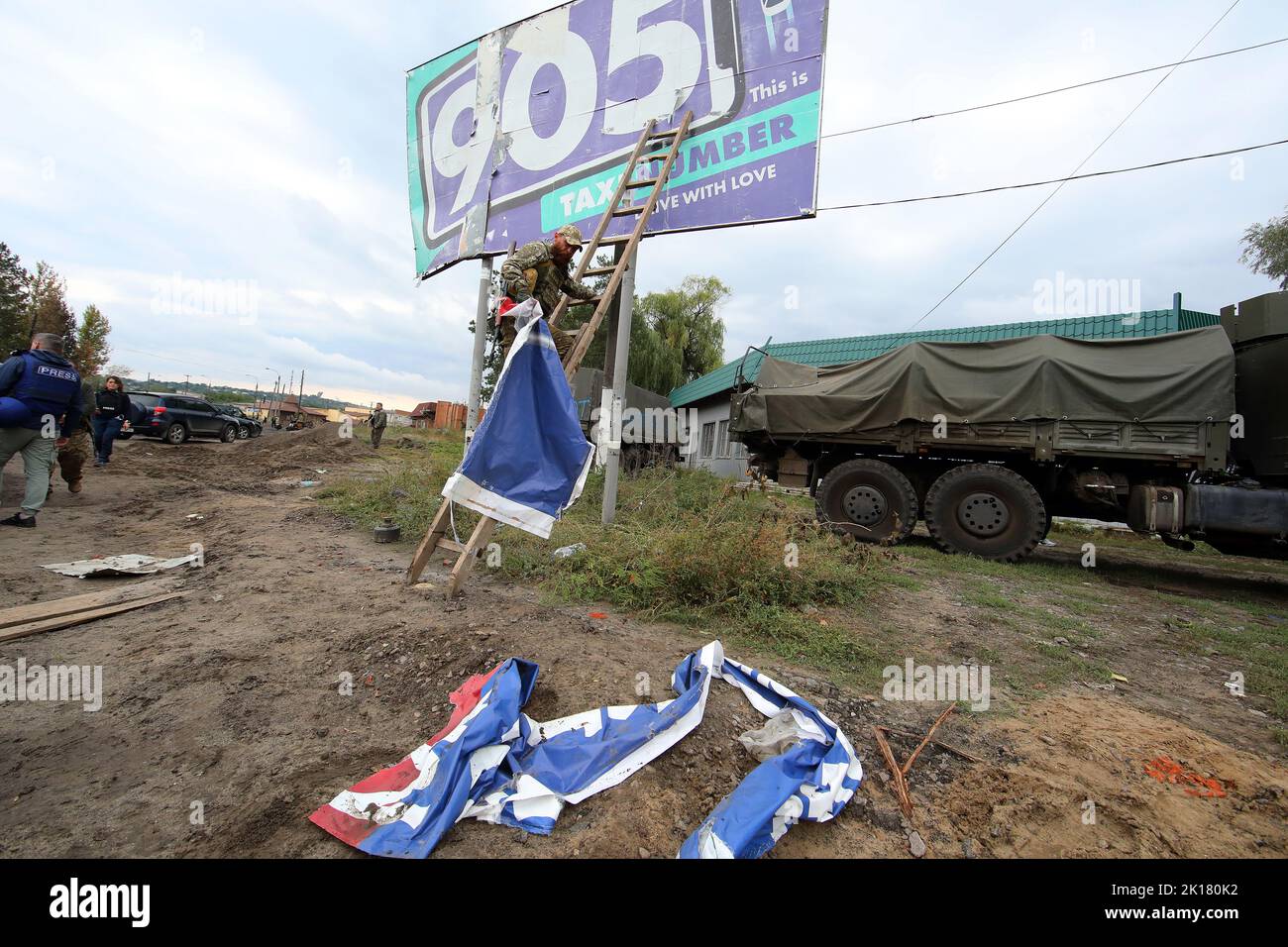 IZIUM, UKRAINE - 15 SEPTEMBRE 2022 - Un militaire ukrainien déchire une bannière de propagande russe à Izium qui a été libérée de russe inv Banque D'Images