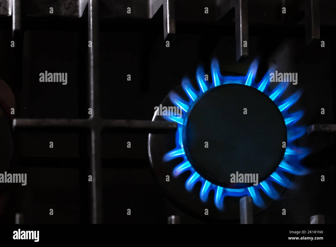 Brûleur à gaz avec une flamme bleue sur une cuisinière de cuisine noire, vue de dessus, foyer doux sélectif, espace de copie. Crise de gaz. Banque D'Images