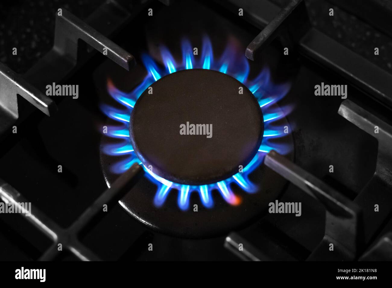 Brûleur à gaz avec une flamme bleue sur une cuisinière de cuisine noire, avec une grille en fonte, vue de dessus, foyer doux sélectif. Crise de gaz. Banque D'Images