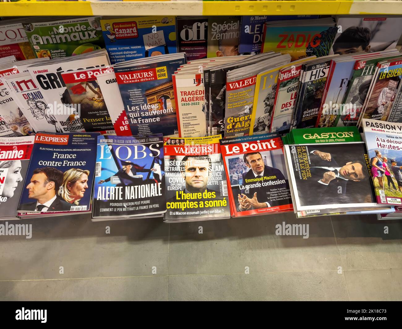 Paris, France - 17 avril 2022: POV main masculin tenant dans un kiosque de presse le dernier numéro de l'Express, l'OBS, Valeurs, le point, Gaston magazines journaux présentant Emmanuel Macron candidat à la présidence française Banque D'Images