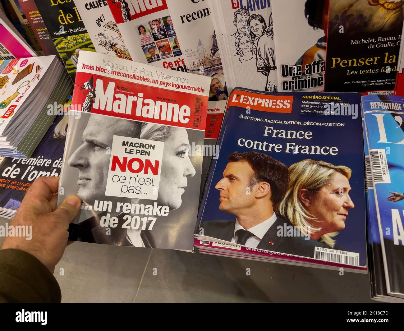 Paris, France - 17 avr 2022: POV main mâle tenant à l'intérieur d'un kiosque de presse le dernier numéro de Marriane avec Macron le Pen non, ce n'est pas un remake du titre de titre de 2017 Banque D'Images