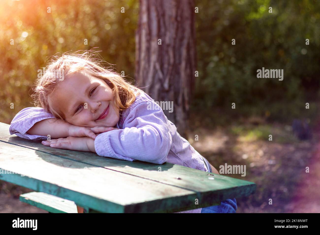 La petite fille se repose dans le parc. L'enfant rêve à l'extérieur par une journée ensoleillée. Banque D'Images