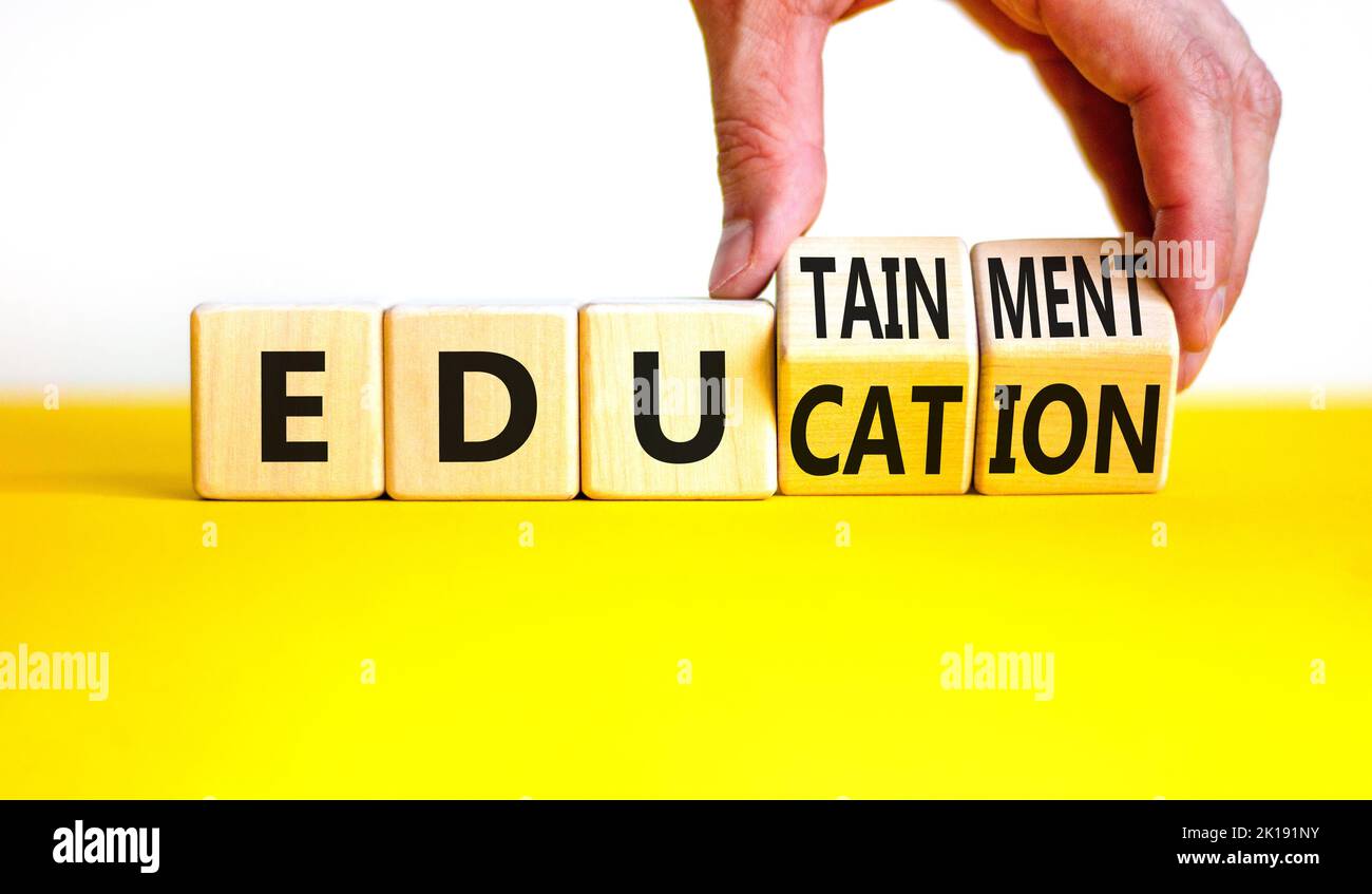 Symbole éducation et divertissement. Concept Words Education et edutainment sur des cubes en bois. Main du professeur. Magnifique table jaune fond blanc. EDUC Banque D'Images