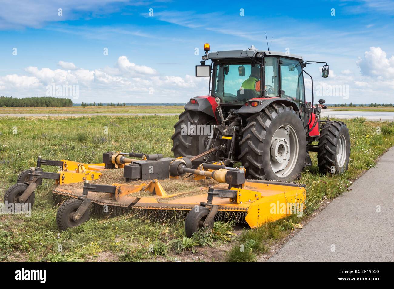 Tracteur à roues avec tondeuse sur route Banque D'Images