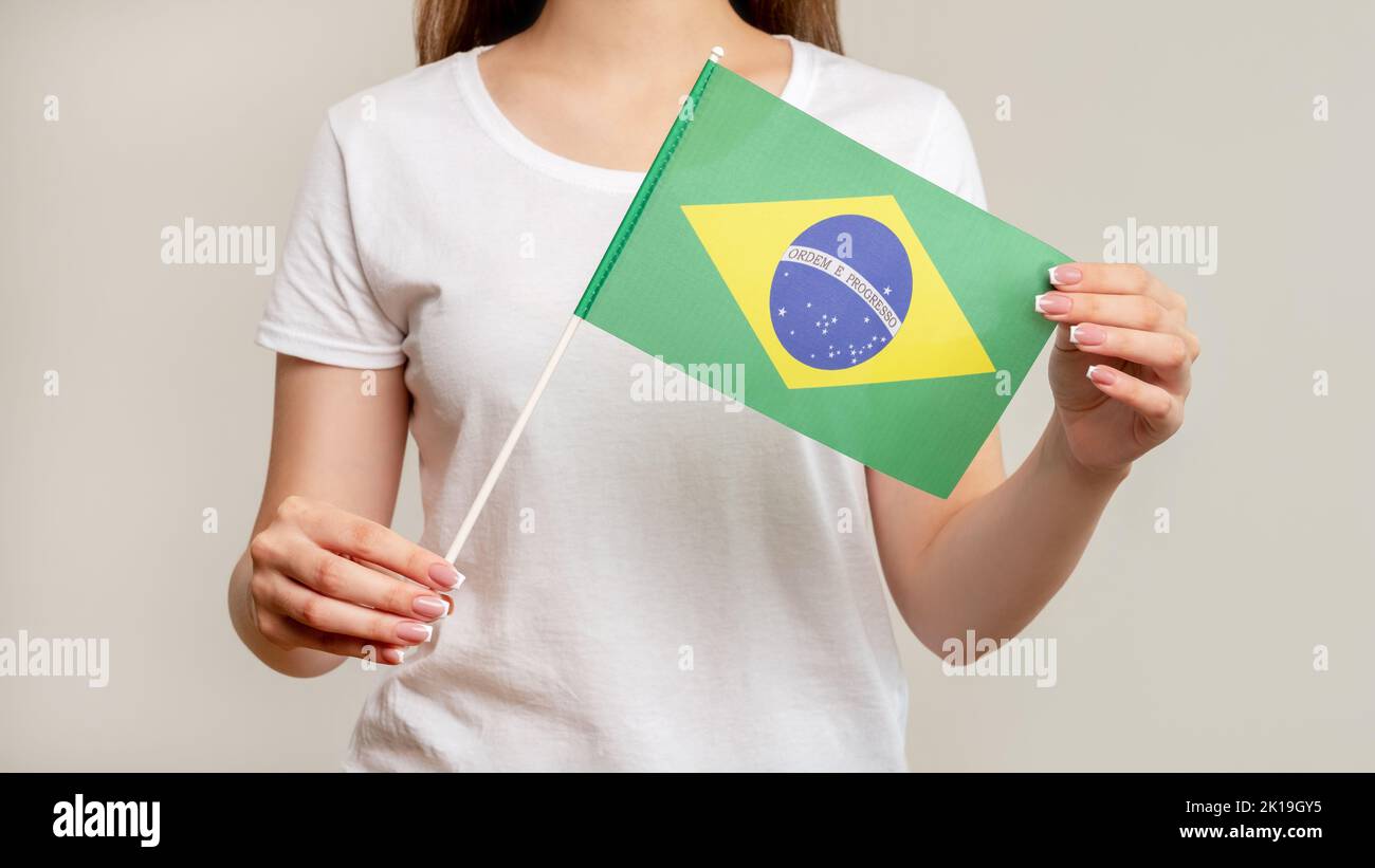 Drapeau du Brésil. Fan de football. Femme en blanc tenant le symbole officiel avec vert jaune diamant bleu globe isolé sur fond neutre flou. National c Banque D'Images