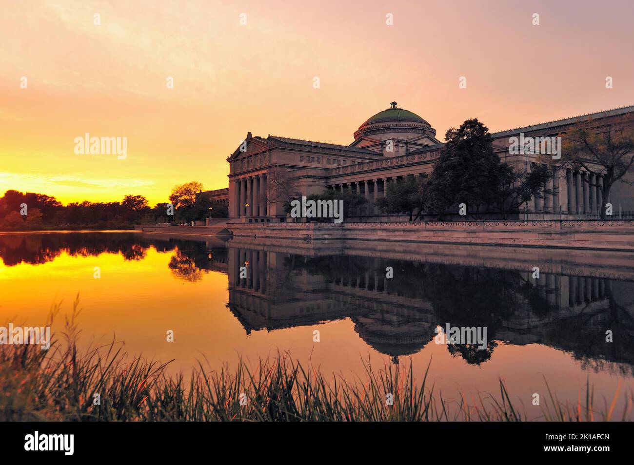Chicago, Illinois, États-Unis. Musée des sciences et de l'industrie fournissant une image miroir dans un étang réfléchissant juste avant le coucher du soleil. Banque D'Images