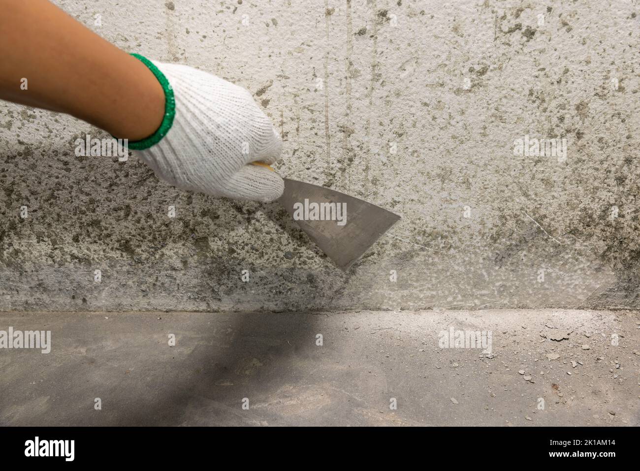 Maison de rénovation , Painter raclant les débris de béton de verser la nouvelle couche de béton sur le vieux plancher. Banque D'Images