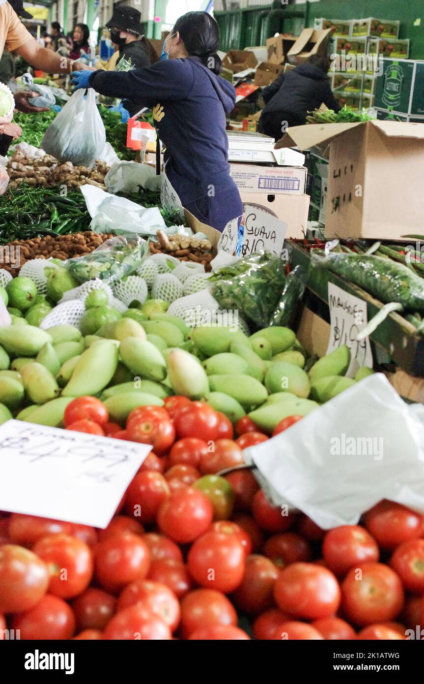 Un vendeur de Paddy’s Market à Flemington, Sydney, vend des mangues vertes, des tomates, des pommes Granny Smith, des haricots et d’autres fruits et légumes frais Banque D'Images