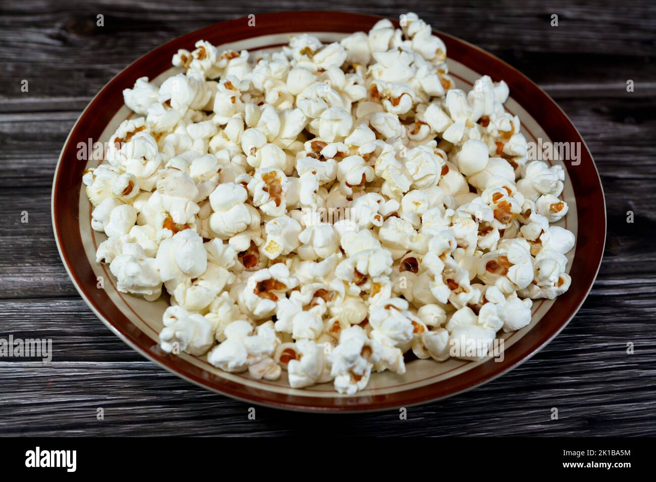 Une plaque de maïs soufflé et également appelé maïs soufflé, popcorns ou maïs pop, variété de grains de maïs qui se dilate et se gonfle lorsqu'il est chauffé isolé sur un woode Banque D'Images