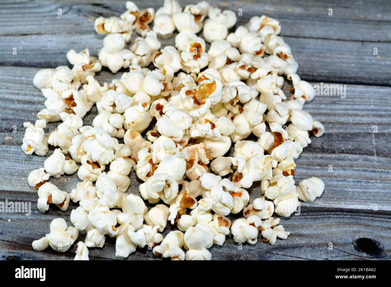 Pile de maïs soufflé et également appelé maïs soufflé, popcorns ou maïs pop, variété de grains de maïs qui se dilate et se gonfle lorsqu'il est chauffé isolé sur un b en bois Banque D'Images