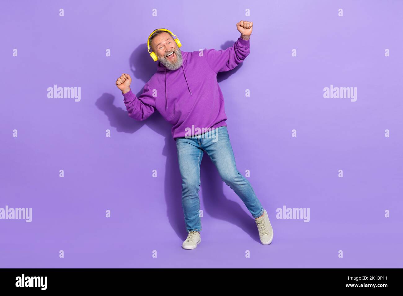 Photo de positif retraité vieux homme habillé violet casque à capuche ont plaisir danse écouter des chansons isolées sur fond violet couleur Banque D'Images