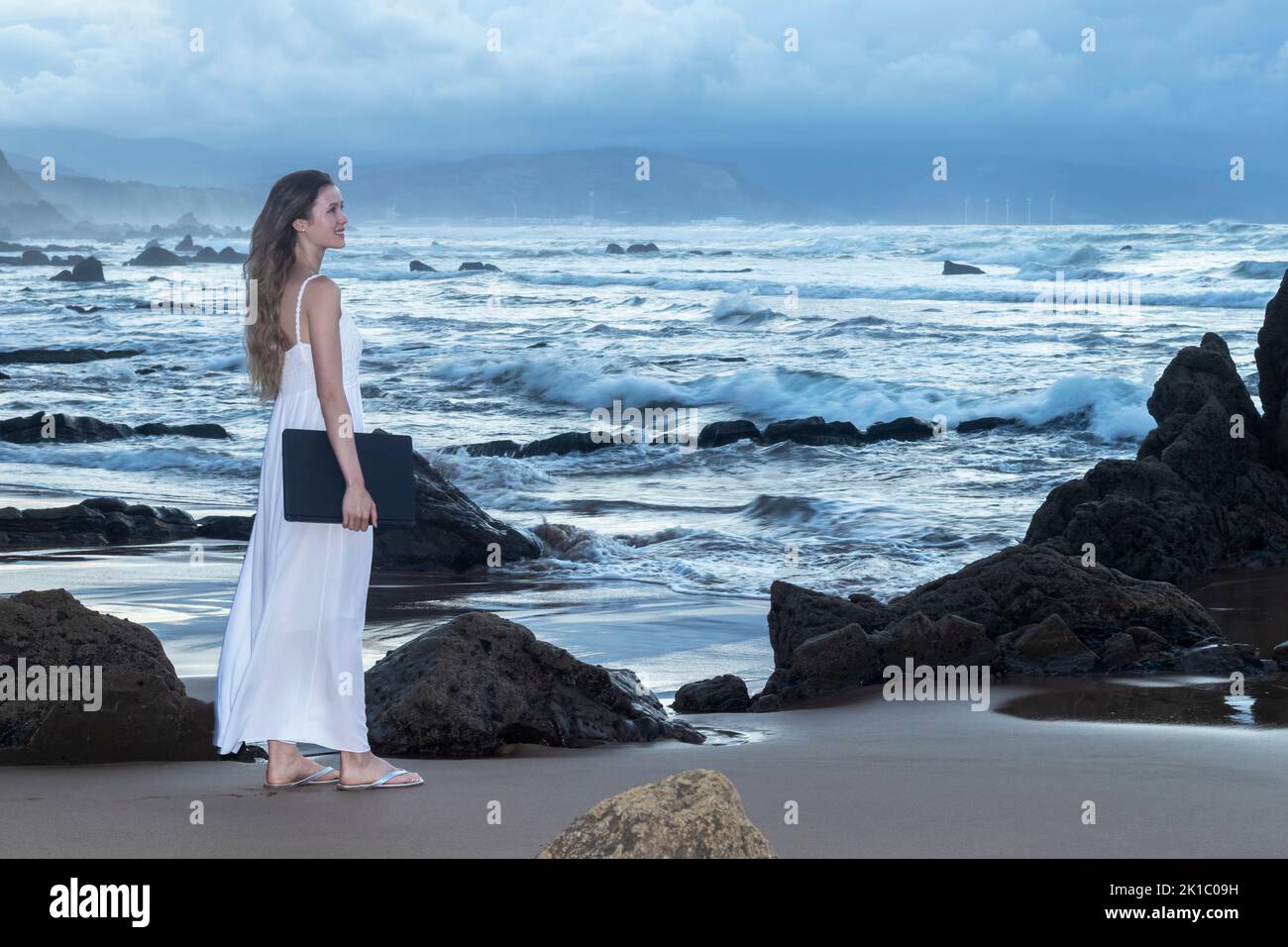 Jeune femme attrayante en robe, travaillant sur un ordinateur portable. Indépendante jeune fille. Concept de nomade numérique Banque D'Images