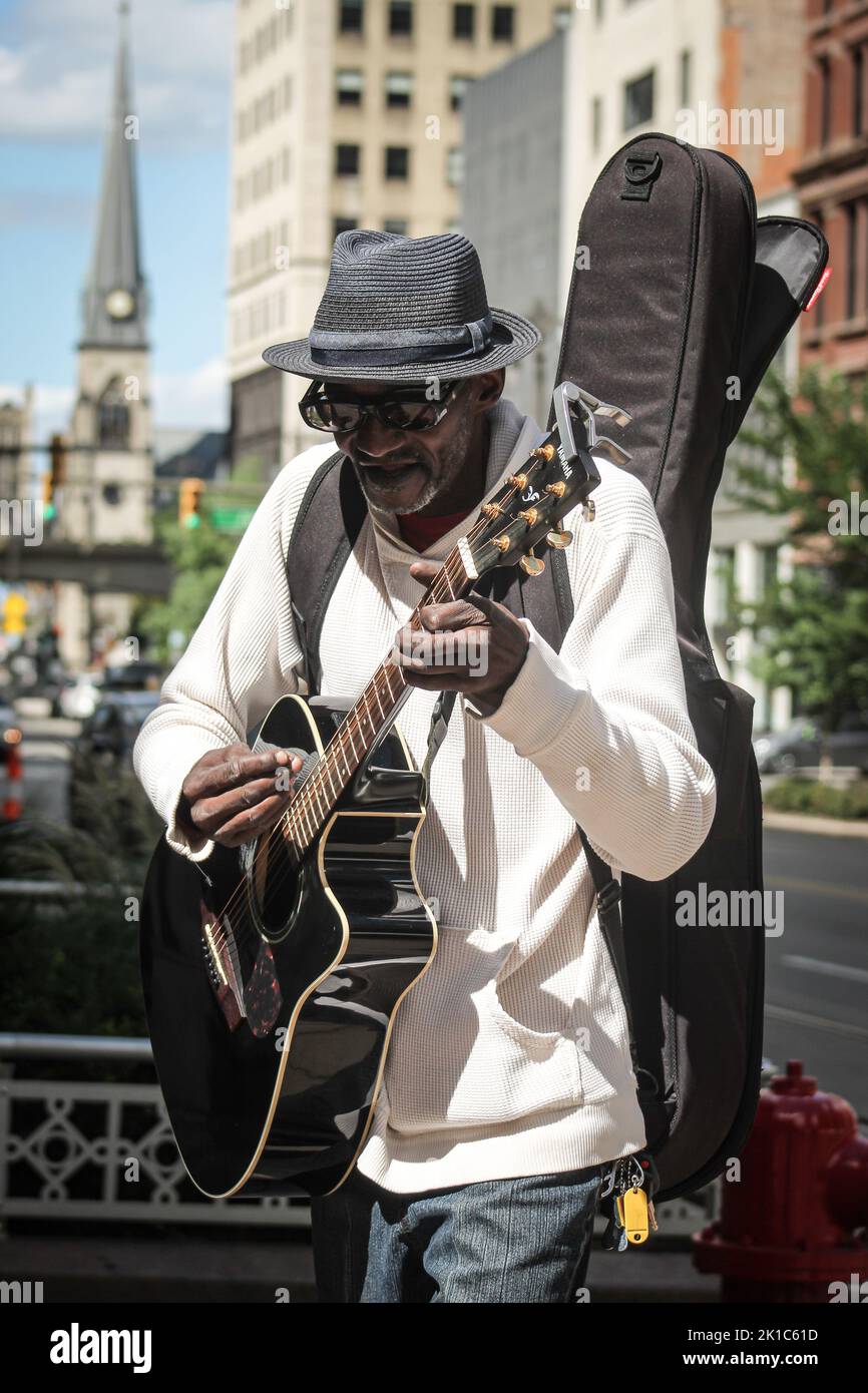 Un cliché vertical d'un musicien de rue souriant avec une guitare à l'extérieur Banque D'Images