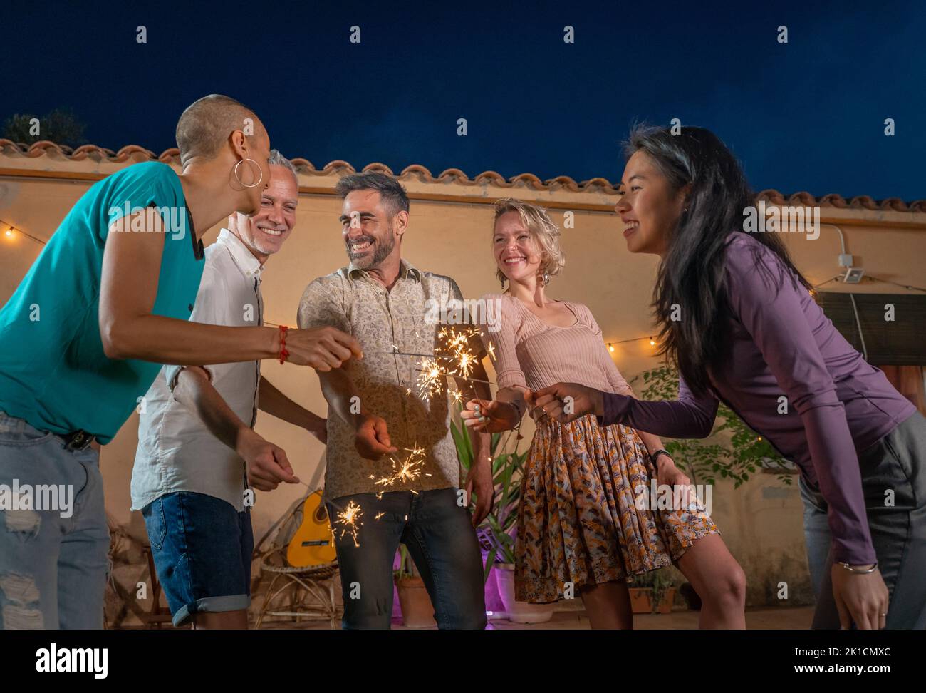 Un groupe d'amis matures fêtent avec éclat lors d'une fête privée dans l'arrière-cour ou dans un club. Des gens heureux et joyeux font la fête dans une discothèque Banque D'Images